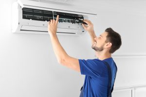 Male technician repairing air conditioner indoors