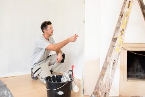 Shot of young handyman painting the wall while renovating apartment.