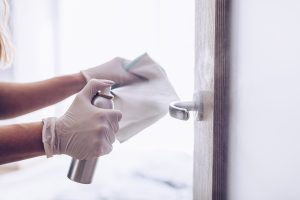 The woman disinfects the door handle with a disinfectant liquid. Coronavirus covid-19 prevention